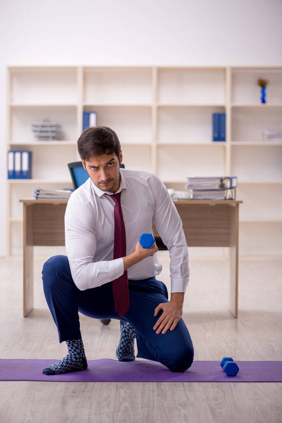 Young employee doing sport exercises during break - Photo, image