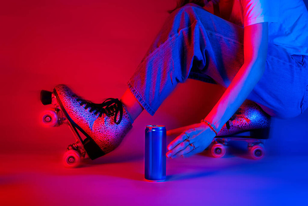 Rolschaatser reikt naar een frisdrank in een blikje tijdens het schaatsen. Sport en recreatie - verzadigd rood en blauw, pop art stijl poster. - Foto, afbeelding