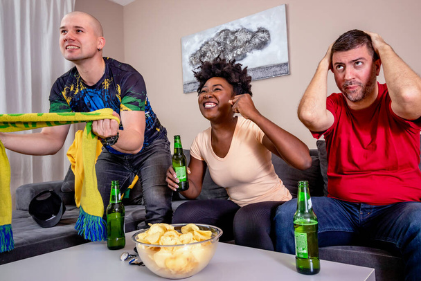 Friends watching a football match on TV, cheering for their national team. World cup in soccer. Brazil fans. - 写真・画像