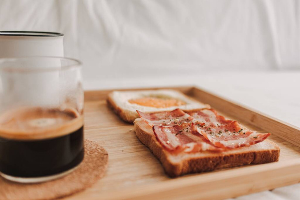 Easy and simple breakfast set of Bacon Sandwich served with black coffee on bed. - 写真・画像