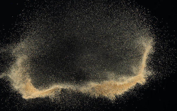 Sand fliegt explosionsartig, Goldene Sandwelle explodiert. Abstrakte Sandwolken fliegen. Gelber Sand spritzt in die Luft. Schwarzer Hintergrund Isolierte High-Speed-Verschluss, werfen Freeze Stop-Motion - Foto, Bild