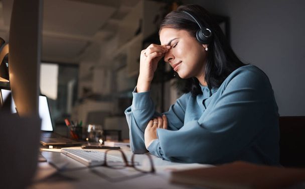 Stress, burnout and overtime, woman in call center with headache at crm office desk. Tired, frustrated and annoyed customer service consultant at computer working late at night with error or glitch - Photo, Image
