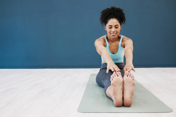 Black woman, yoga mat or studio stretching in pilates healthcare class or zen wellness center on blue wall mockup. Smile, happy or relax yogi in flexibility workout training or fitness floor exercise. - 写真・画像