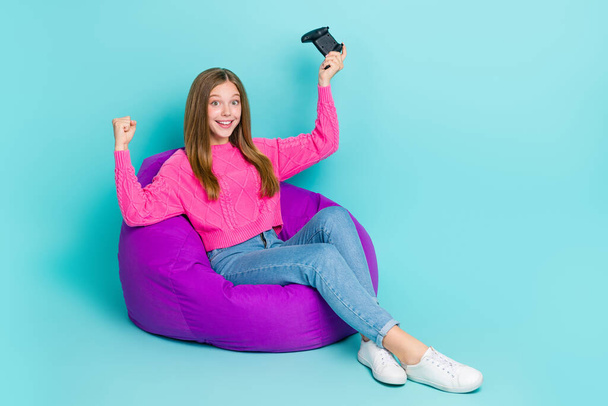 Full length photo of cheerful lady sit chair raise hand fist celebrate success achievement empty space isolated on cyan color background. - Foto, imagen