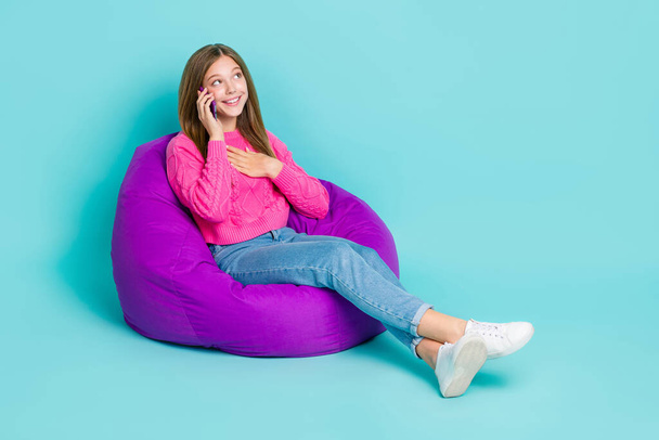 Full length photo of positive pretty lady sit chair speaking chatting device gadget look empty space isolated on cyan color background. - Foto, Imagem
