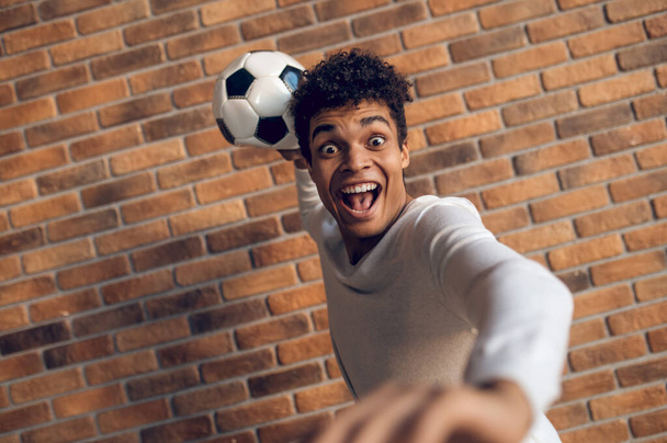 Screaming player standing against the brick wall and throwing the ball with one hand from behind - Fotoğraf, Görsel