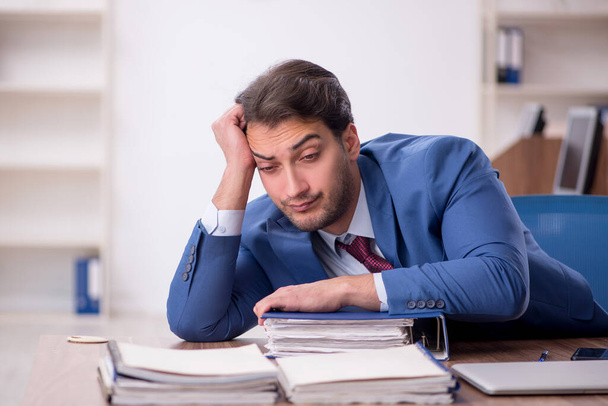 Young businessman employee unhappy with excessive work at workplace - 写真・画像