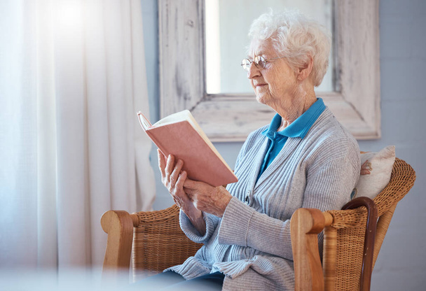 Książka, czytanie i starsza kobieta w domu na emeryturze w okularach i spokojnej mentalności, wiedzy i uczenia się na kanapie krzesła. Starsza lub starsza kobieta z literaturą, językiem i historią miłosną w salonie. - Zdjęcie, obraz