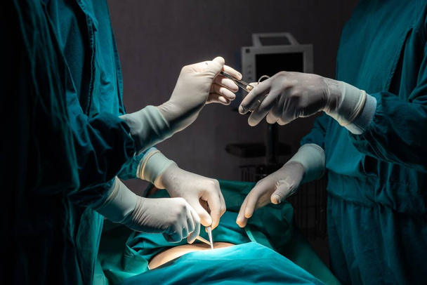 Imagen del equipo quirúrgico realiza operación quirúrgica, enfermera reparte tijeras estériles al cirujano como apoyo y cooperativo en concepto de sala de operaciones. - Foto, Imagen