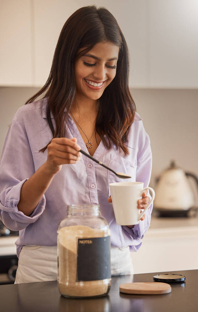 Kadın, gülümse ve sabah rutin işler için mutfakta kahve yap, evde günlük hazırlıklara başla. Kadın gülümsüyor ve tatlı sıcak içecek ya da kafein için kupaya şeker ekliyor.. - Fotoğraf, Görsel