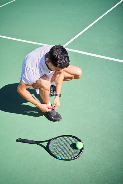 Tennis, tie and man with shoes on a court for sports training, fitness exercise or cardio workout in summer in Spain. Wellness, athlete or tennis player ready to start playing a game on tennis court. - Foto, Imagem