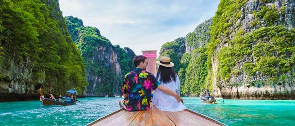 タイ人女性と白人男性は、ピピ島のラグーンにあるロングテールボートの前にいます。ピラゴンタイ｜コ・ピピ - 写真・画像