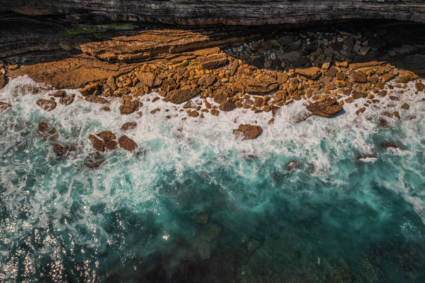 Вода, разбивающая камни, чистая красота. Астурийское побережье, захваченное беспилотником летом. Скалы с камнями и водой. - Фото, изображение