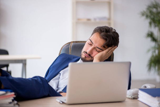 Young businessman employee extremely tired at workplace - Foto, imagen