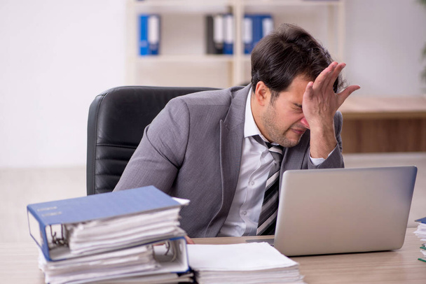 Joven empleado descontento con el exceso de trabajo en la oficina - Foto, imagen