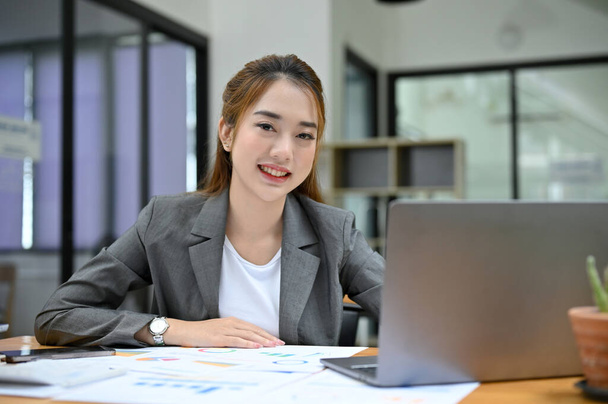 Attractive and gorgeous young Asian female businesswoman or female financial analyst working at her office desk. - 写真・画像