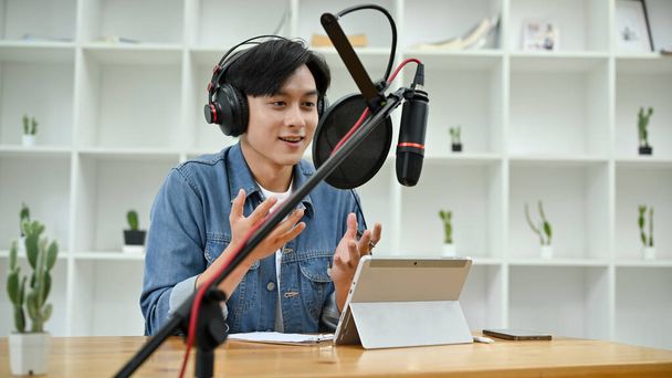 Talentuoso e professionale conduttore radiofonico asiatico maschio o podcaster che gestisce il suo spettacolo nel suo studio, raccontando i suoi contenuti audio al suo pubblico online. - Foto, immagini