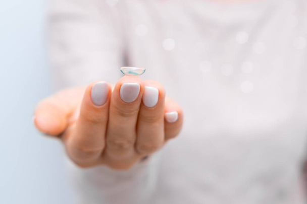 Cierre mujer sosteniendo lente en la punta del dedo - Foto, imagen