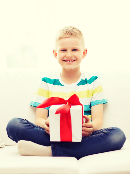 smiling little holding gift box sitting on couch - Fotoğraf, Görsel