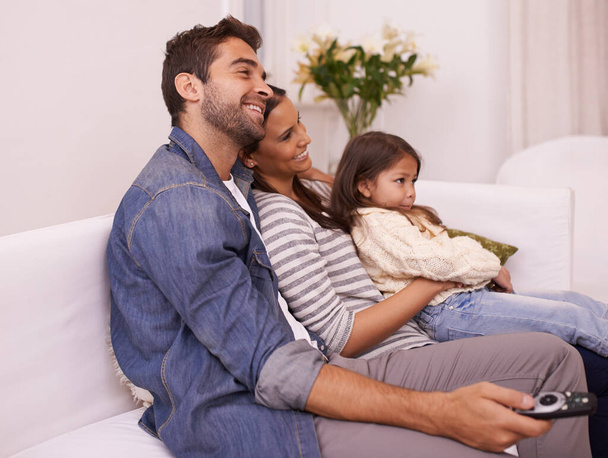 漫画を見ましょう。若い家族がソファに座ってテレビを見ながら - 写真・画像