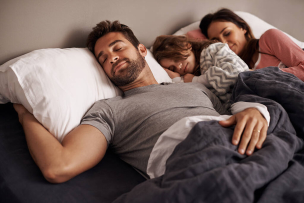 Kuschelig zwischen Mama und Papa. ein kleines Mädchen schläft neben ihren Eltern im Bett - Foto, Bild
