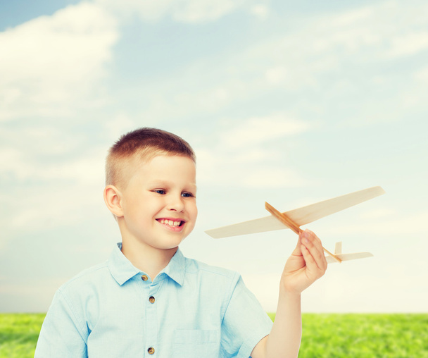 petit garçon souriant tenant un modèle d'avion en bois
 - Photo, image