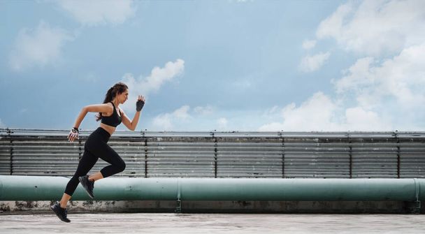 Nainen urheilija tekee juoksu ja syöksy liikunta harjoitus katolla. - Valokuva, kuva