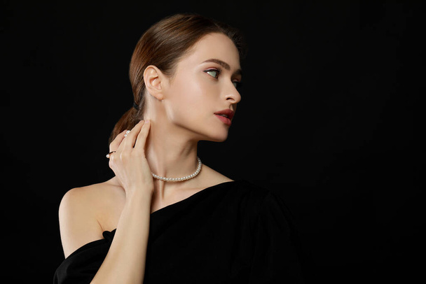 Young woman wearing elegant pearl jewelry on black background, space for text - Zdjęcie, obraz