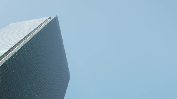 Plan rapproché steadicam à faible angle de l'immeuble de bureaux moderne en façade de verre dans le quartier des affaires avec miroir mural à lunettes avec ciel bleu dans le quartier financier - Séquence, vidéo