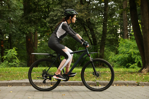 Young woman riding bicycle on road outdoors - Foto, Bild