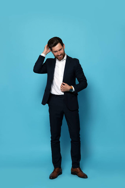 Smiling bearded man in suit on light blue background - Foto, afbeelding