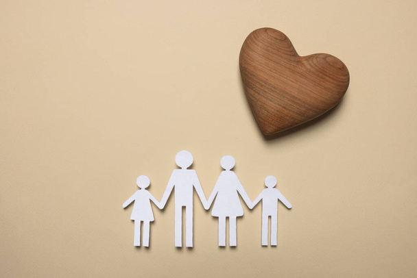 Paper family figures and wooden heart on beige background, flat lay. Insurance concept - 写真・画像