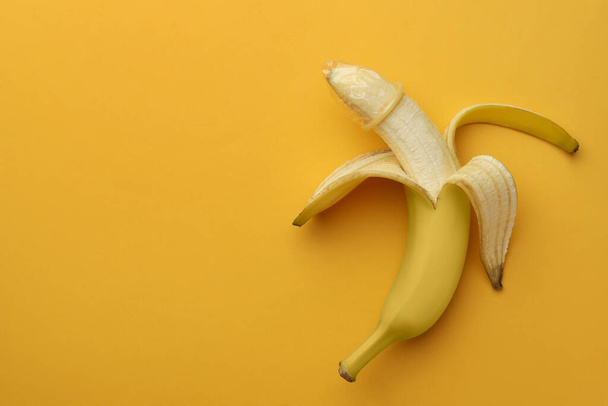 Banana with condom on orange background, top view and space for text. Safe sex concept - Foto, afbeelding