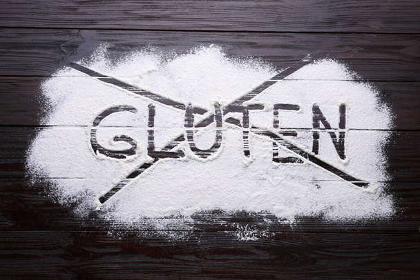 Crossed out word Gluten written with flour on dark wooden table, top view - Zdjęcie, obraz