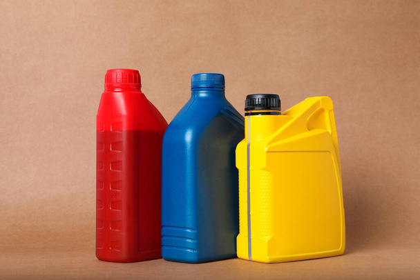 Motor oil in different canisters on light brown background - Foto, Imagen