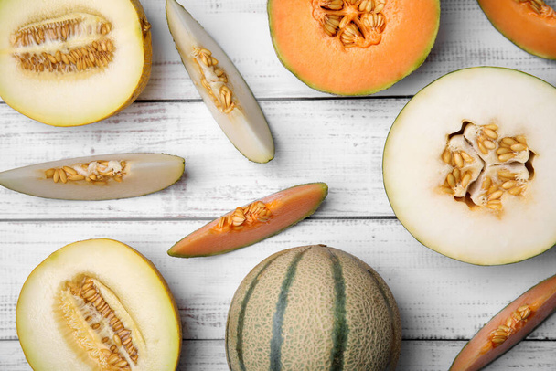 Tasty colorful ripe melons on white wooden table, flat lay - Photo, Image