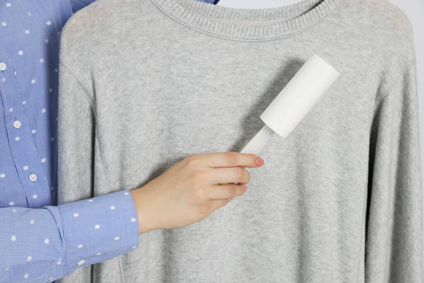 Woman cleaning clothes with lint roller, closeup - Fotoğraf, Görsel