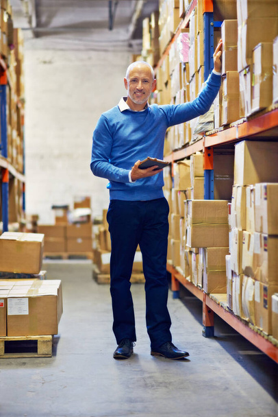 Hes in charge. A man standing next to industrial shelving with boxes - Photo, Image