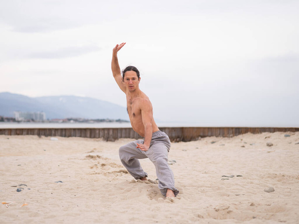 Caucasian man with long hair practicing qigong outdoors - Foto, afbeelding