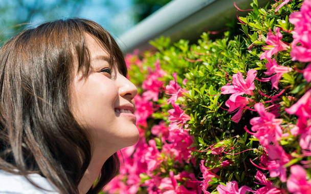 jong japans meisje ruiken mooie bloemen. - Foto, afbeelding