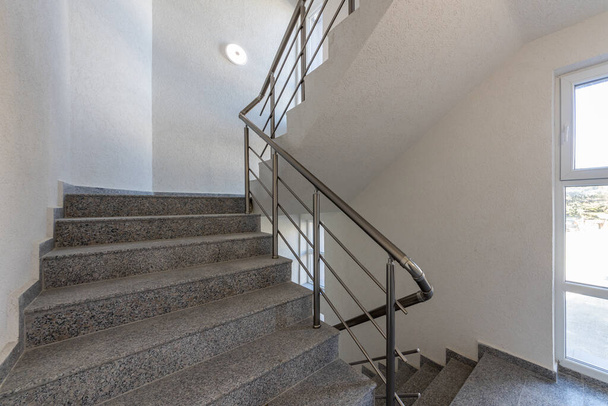 床と床の間のモダンな階段ケース。近代的な建物内の金属レール付きの階段 - 写真・画像