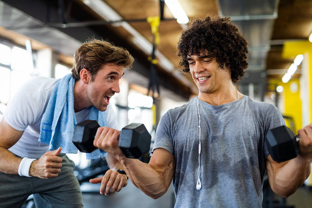 Fitness, sport, exercising and diet concept. Happy fit man exercising together with his personal trainer, friend in gym. - Fotoğraf, Görsel