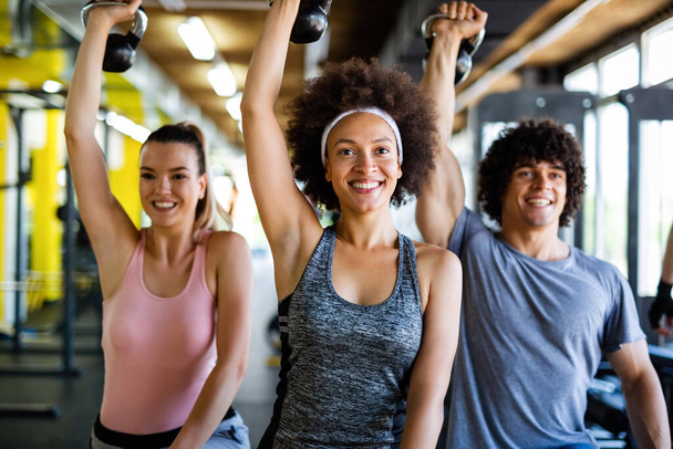 Group of sportive fit people working out in a gym. Multiracial friends exercising together in fitness club. - Zdjęcie, obraz