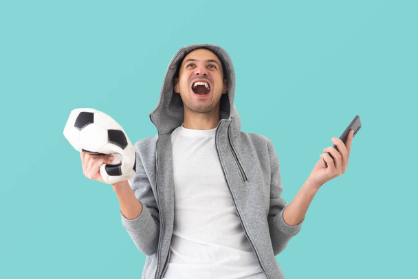 αρσενικό ανεμιστήρα ποδοσφαίρου με μια τσαλακωμένη μπάλα και smartphone. - Φωτογραφία, εικόνα