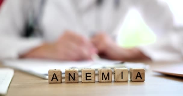 Iscrizione di anemia su cubi di legno sul tavolo, primo piano. Visita da un ematologo, prevenzione e trattamento - Filmati, video