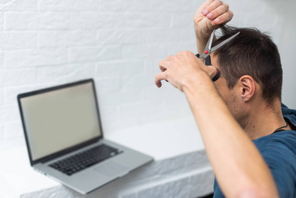 un uomo guarda un taglio di capelli su un computer portatile, tutoraggio di parrucchiere online su un computer portatile. - Foto, immagini
