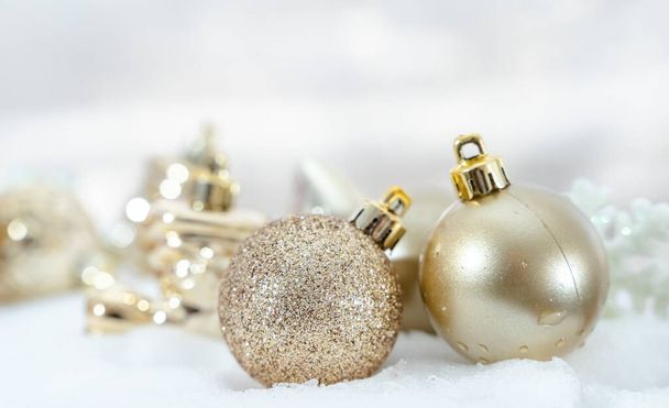 Vánoce zimy - Vánoční míče se stuhou na sněhu, koncept zimních prázdnin. Vánoční červené koule, zlaté koule, borovice a vločky dekorace ve sněhu pozadí - Fotografie, Obrázek