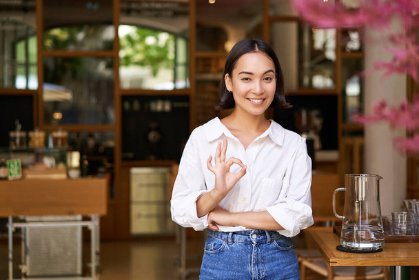 Sonriente mujer asiática feliz, empresario recomendando café, mostrando bien, ok signo de aprobación. Copiar espacio - Foto, Imagen