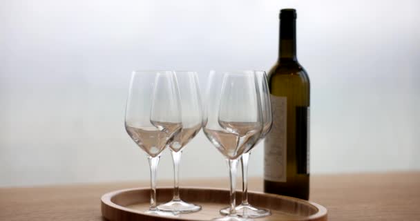 Prázdné sklenice na dřevěném podnose a láhev vína, detailní záběr, zpomalení. Ochutnávka alkoholického nápoje - Záběry, video