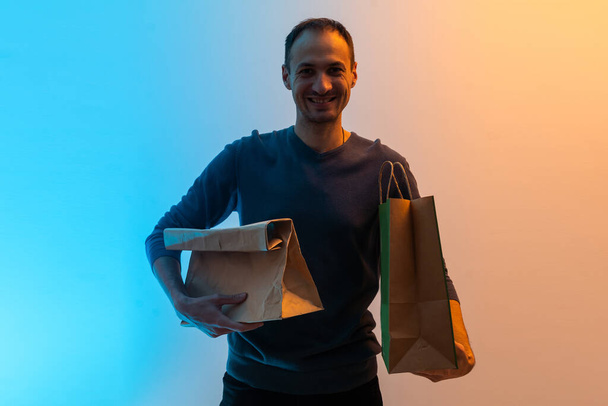 Zusteller halten Bastelpapierpäckchen mit Lebensmitteln isoliert auf farbigem Hintergrund. - Foto, Bild